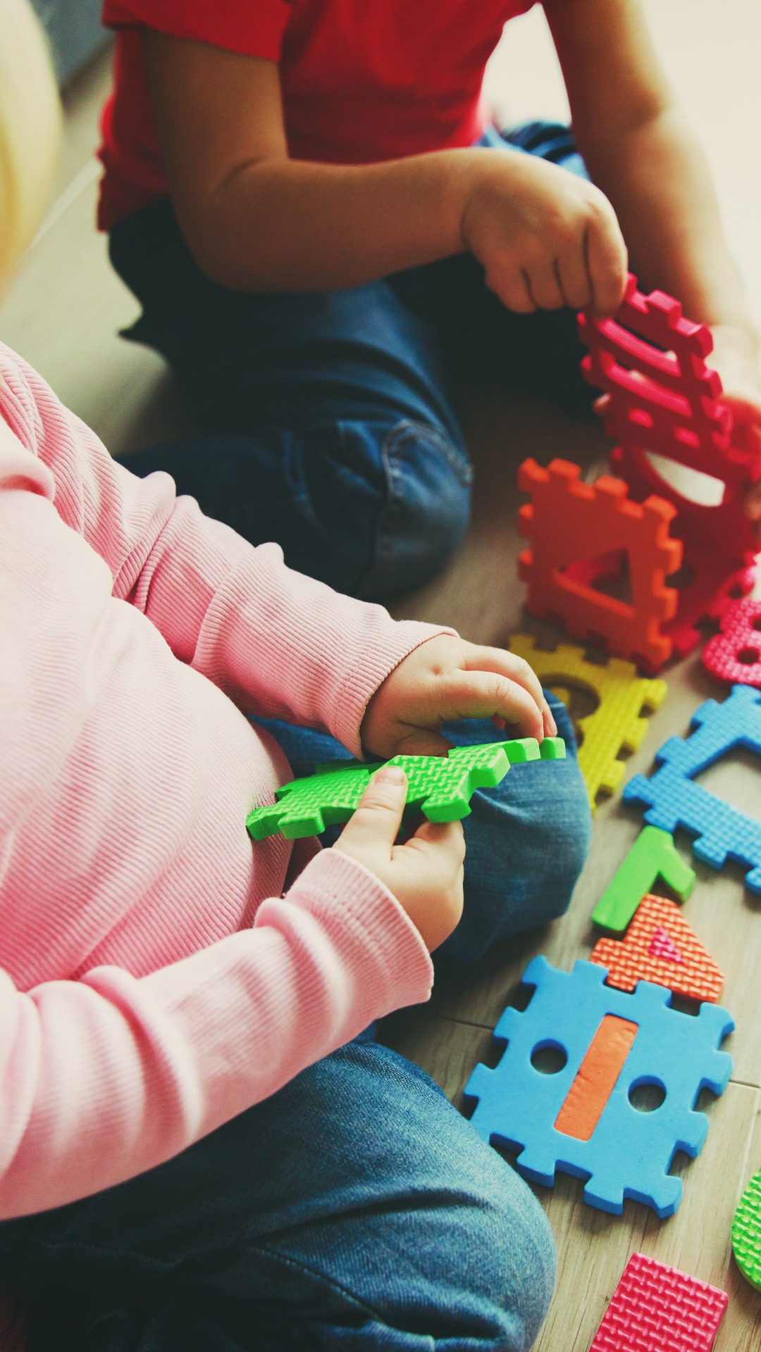 Cute little boy and girl playing with colorful wooden blocks at home